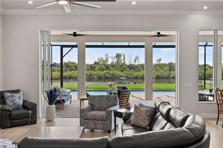 Expansive sliding glass doors opening to a screened lanai with a pool and waterway beyond