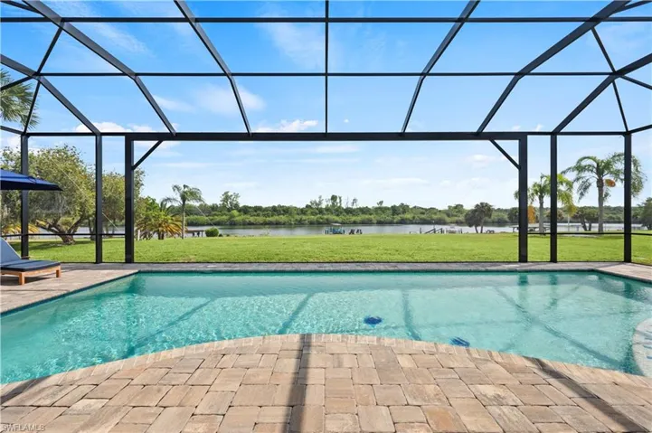 Screened outdoor living area featuring a swimming pool, paver deck, and direct waterfront access