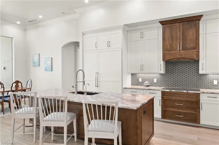 Gourmet kitchen featuring a large island with an integrated sink, stone countertops, and a subway tile backsplash