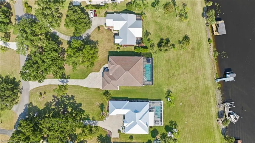 Aerial perspective showcasing a property with a spacious backyard, private swimming pool, and direct waterfront access