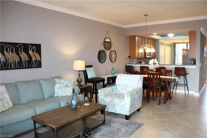 Living room with ornamental molding, light tile patterned floors, and hanging lights