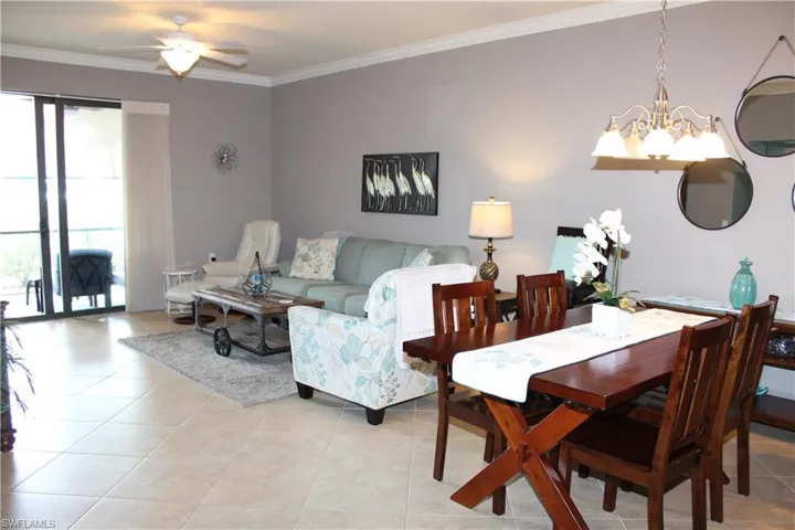 Dining space featuring hanging lights, light tile patterned floors, crown molding, and ceiling fan