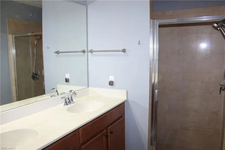 Full bathroom with double vanity and a shower stall