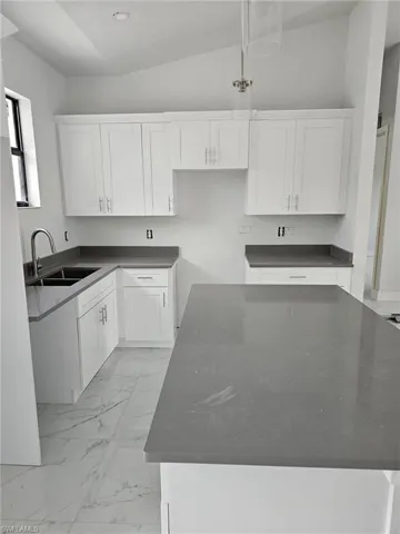 Kitchen featuring pendant lighting, white cabinetry, lofted ceiling, and light tile patterned floors