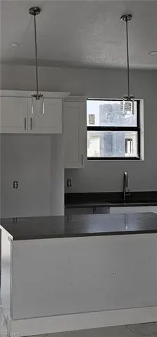 Kitchen with sink, pendant lighting, and white cabinets