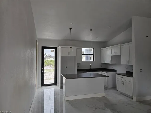 Kitchen featuring white cabinetry, a center island, light tile patterned floors, and a wealth of natural light