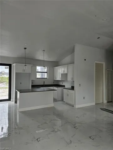 Kitchen featuring white cabinetry, sink, a center island, and light tile patterned floors
