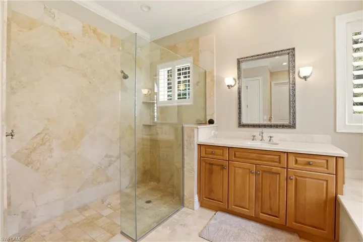 Bathroom with crown molding, vanity, and a stall shower