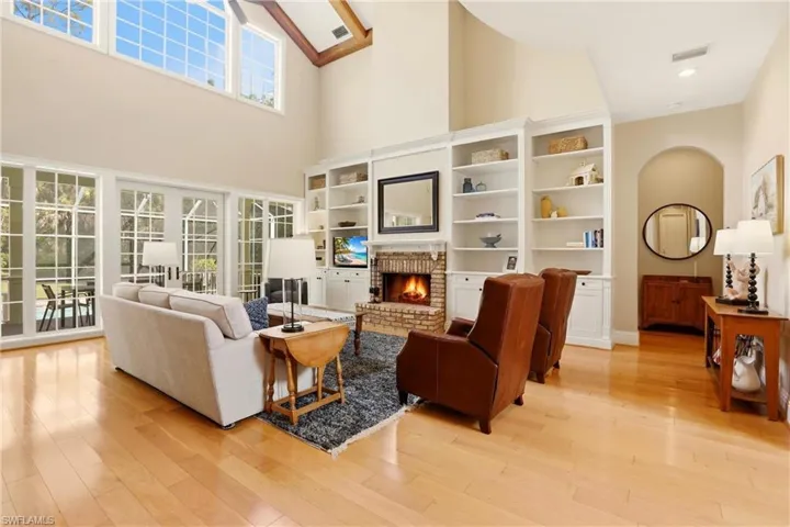 Living room featuring a brick fireplace, light wood-type flooring, and a high ceiling