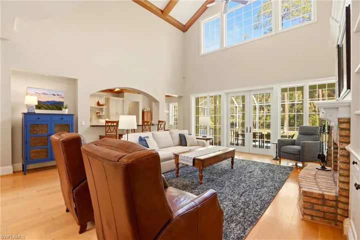 Living area with light wood finished floors, french doors, arched walkways, and lofted ceiling