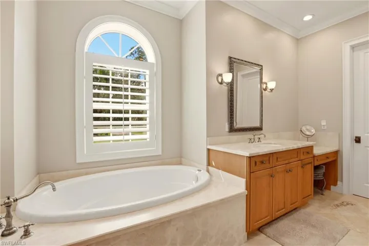 Bathroom with vanity, crown molding, a bath, and recessed lighting