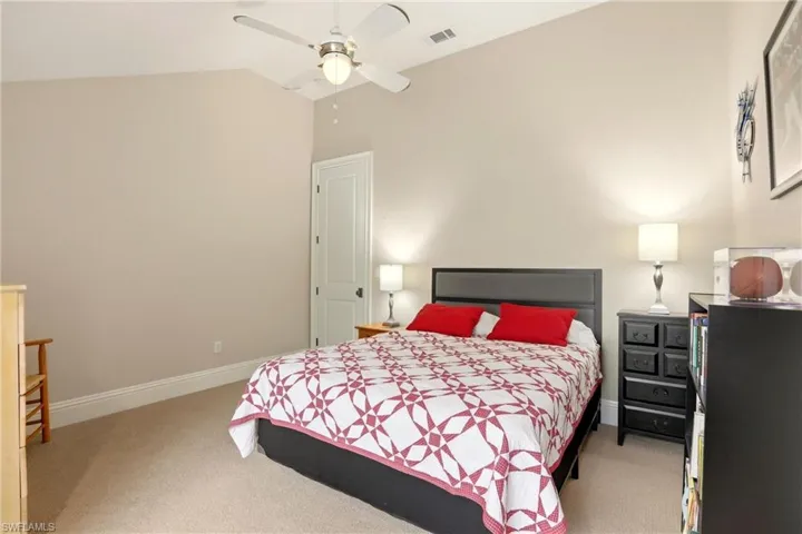 Bedroom with lofted ceiling, light colored carpet, and a ceiling fan