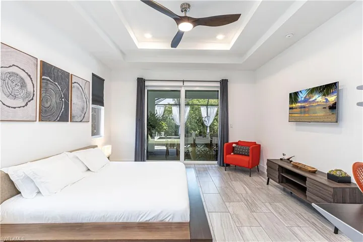 Bedroom featuring a tray ceiling, access to exterior, recessed lighting, ceiling fan, and baseboards