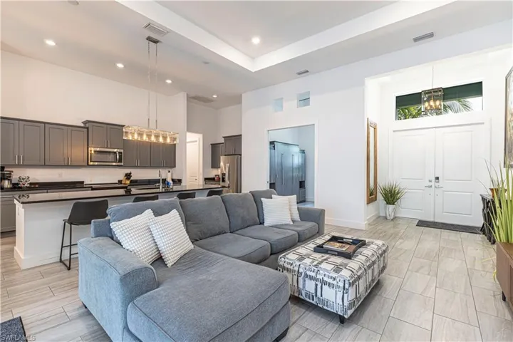 Living area featuring a towering ceiling, recessed lighting, a chandelier, and baseboards