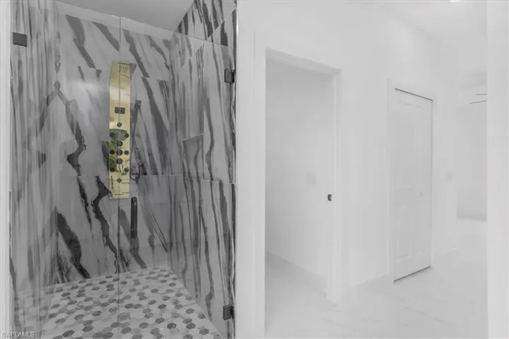 Bathroom with a marble finish shower and light marble finish flooring