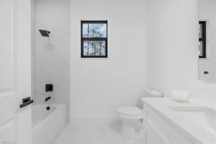 Full bath with vanity, tub / shower combination, and light marble finish flooring