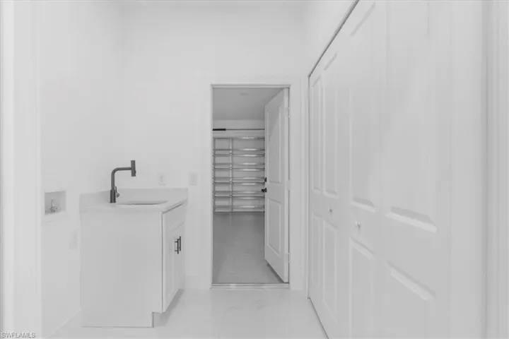 Bathroom featuring vanity, light marble finish floors, and a closet