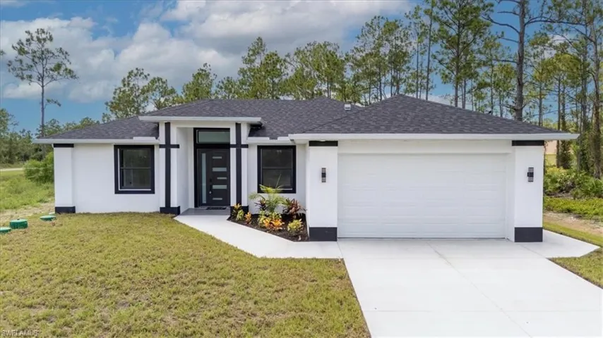 View of front facade with roof with shingles, stucco siding, a front lawn, and a garage