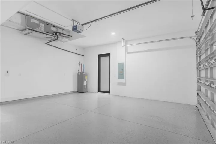 Garage featuring electric water heater, electric panel, and a garage door opener