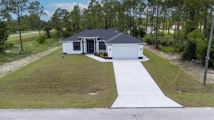 View of front of home featuring concrete driveway, stucco siding, a front yard, roof with shingles, and an attached garage