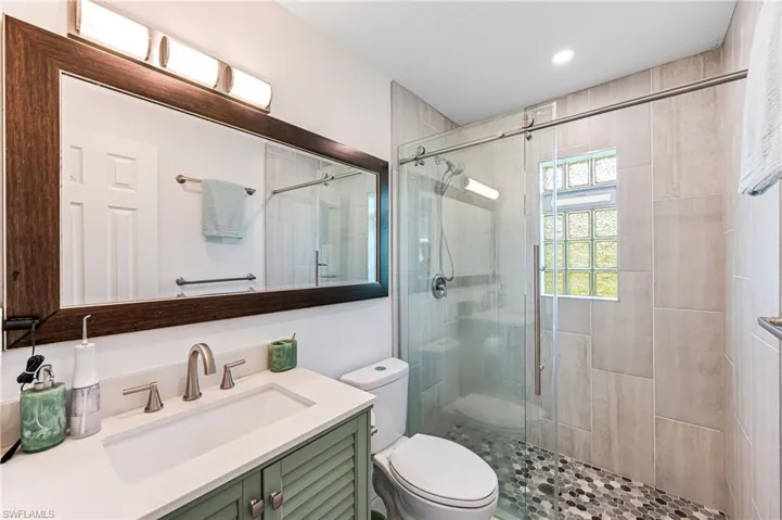 Bathroom with vanity, toilet, and a shower with door