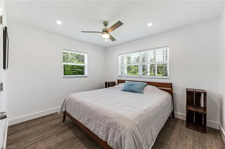 Bedroom with dark hardwood / wood-style flooring, multiple windows, and ceiling fan