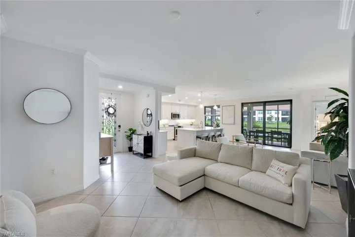 Living room featuring light tile patterned floors, baseboards, recessed lighting, and ornamental molding