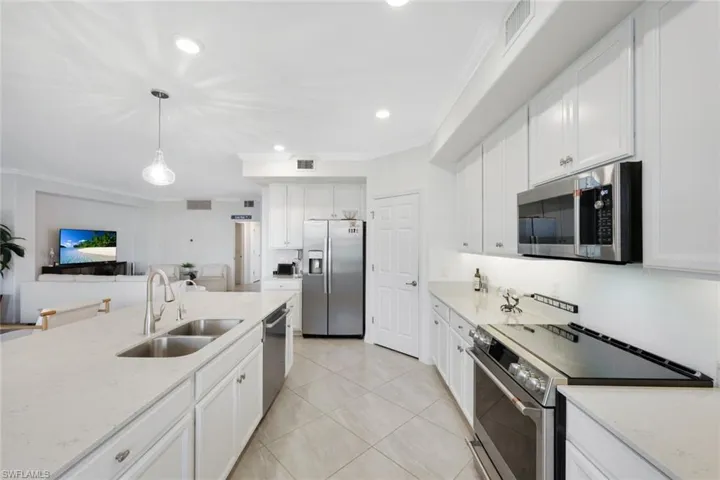 Kitchen with appliances with stainless steel finishes, a sink, crown molding, white cabinets, and recessed lighting