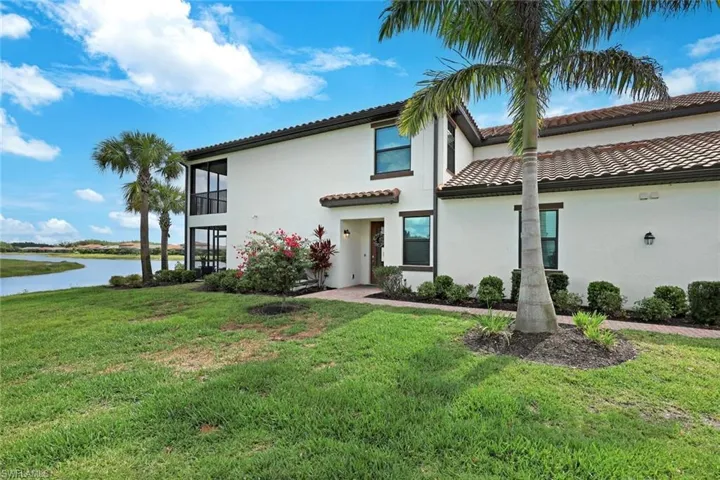 Mediterranean / spanish home with a water view, a tile roof, a front yard, and stucco siding