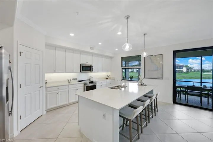 Kitchen with appliances with stainless steel finishes, light tile patterned floors, a sink, plenty of natural light, and ornamental molding