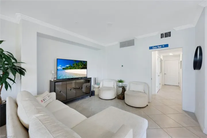 Living room with crown molding, baseboards, and light tile patterned floors