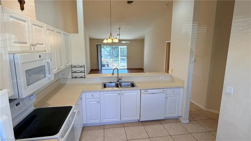 Right Unit: Kitchen with light countertops, white appliances, white cabinets, a chandelier, and light tile patterned floors