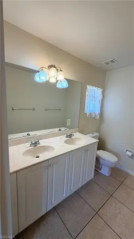 Right Unit: Bathroom featuring double vanity and light tile patterned floors