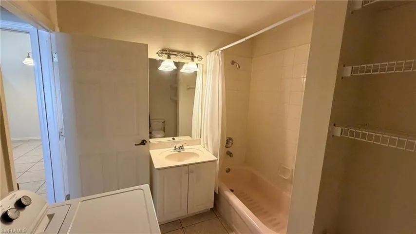Right Unit: Full bathroom with vanity, light tile patterned floors, shower / tub combo, and washer / clothes dryer