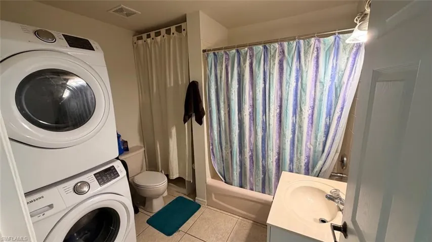 Left Unit: Bathroom with vanity, light tile patterned floors, and shower / tub combo