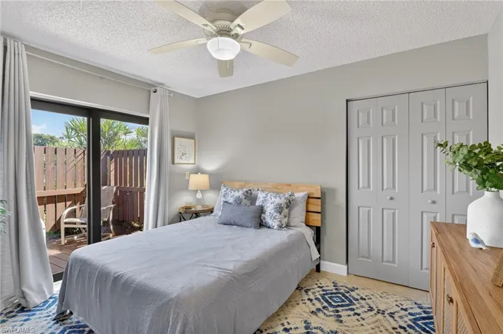Bedroom with access to outside, ceiling fan, a textured ceiling, tile patterned flooring, and a closet
