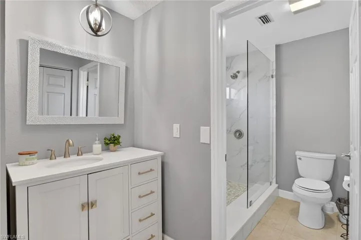 Full bath featuring vanity, a marble finish shower, and light tile patterned floors