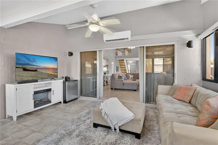 Living area with a textured wall, ceiling fan, and a fireplace