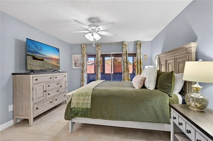 Bedroom featuring a textured ceiling, a ceiling fan, and light tile patterned floors