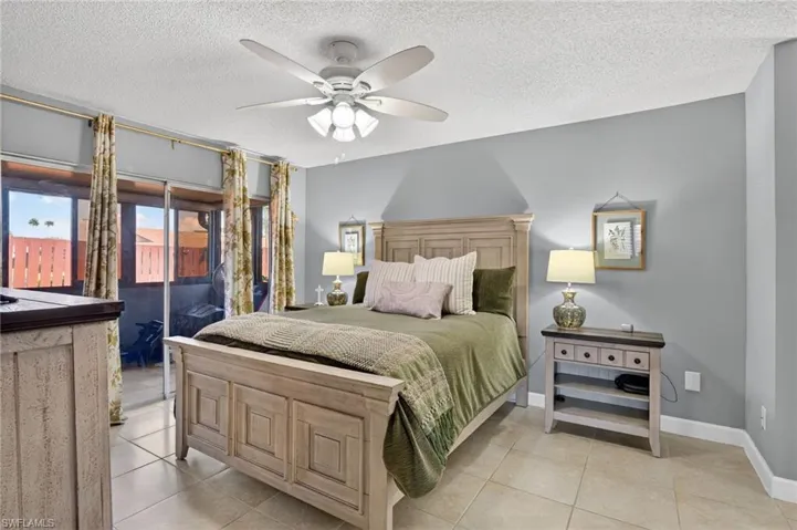 Bedroom with access to exterior, a textured ceiling, ceiling fan, and light tile patterned floors
