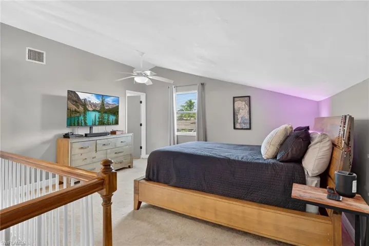 Carpeted bedroom with vaulted ceiling and ceiling fan