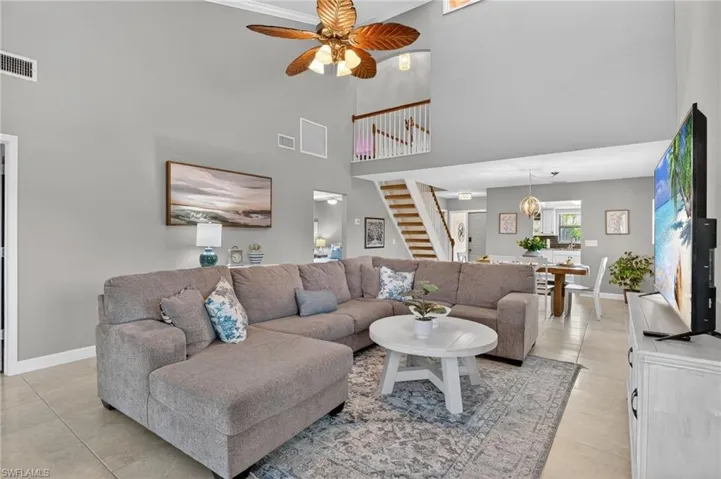 Living area featuring ceiling fan, a high ceiling, and light tile patterned floors