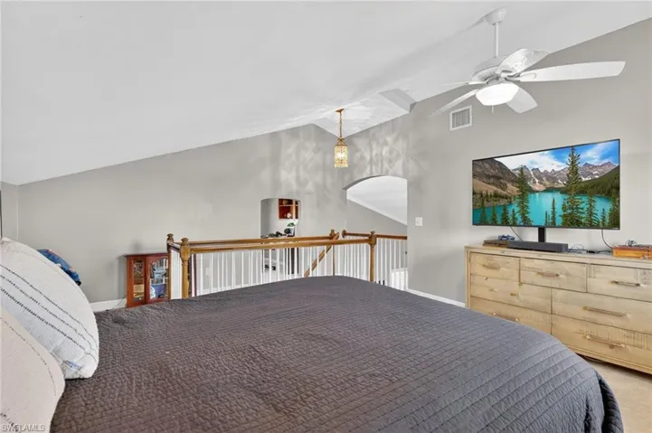 Carpeted bedroom featuring vaulted ceiling and ceiling fan