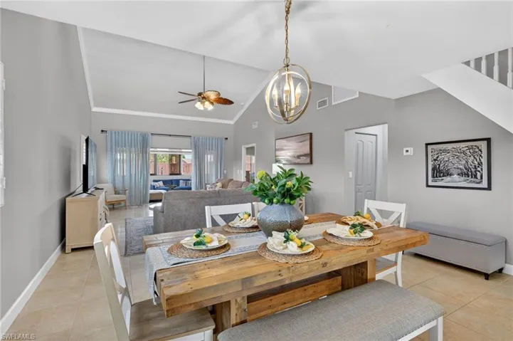 Dining space featuring light tile patterned flooring, a ceiling fan, vaulted ceiling, and hanging lights