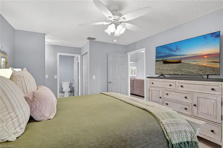 Bedroom with ensuite bath, a textured ceiling, ceiling fan, and a closet