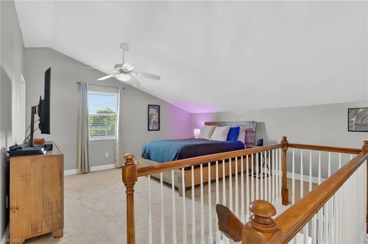 Bedroom featuring lofted ceiling, light colored carpet, and a ceiling fan
