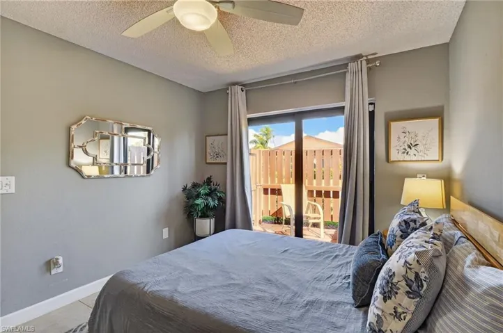 Bedroom with multiple windows, access to outside, a ceiling fan, and a textured ceiling