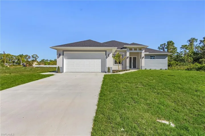 Prairie-style home with a front yard, a garage, driveway, and stucco siding