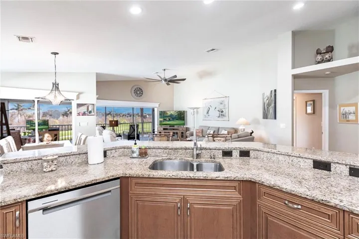 Kitchen featuring dishwasher, sink, light stone counters, and ceiling fan