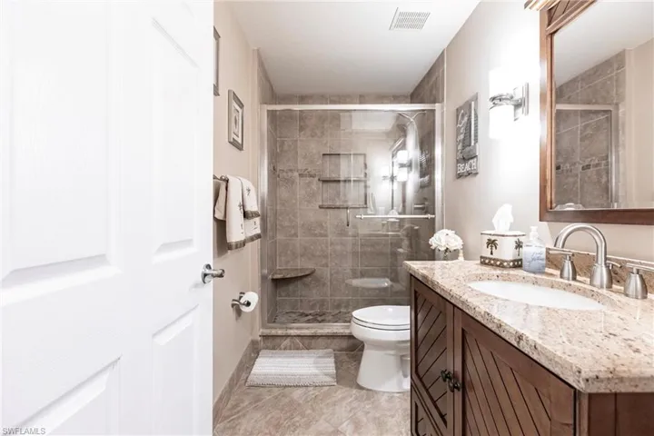 Bathroom featuring toilet, an enclosed shower, vanity, and tile patterned floors